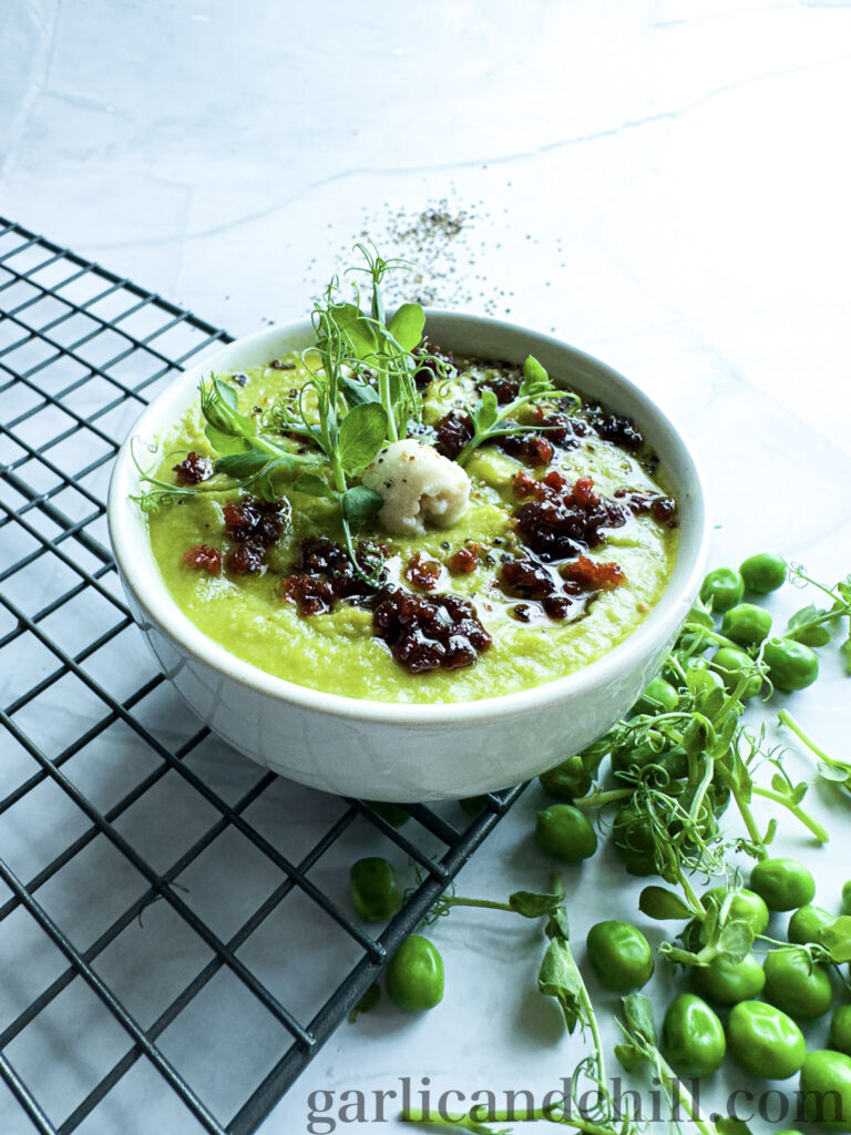 Vegan Fresh Pea Shoot Soup w/ Bac'n Oil in bowl with toppings (side)